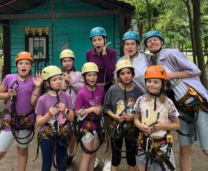 Camp kids wearing harnesses making silly faces